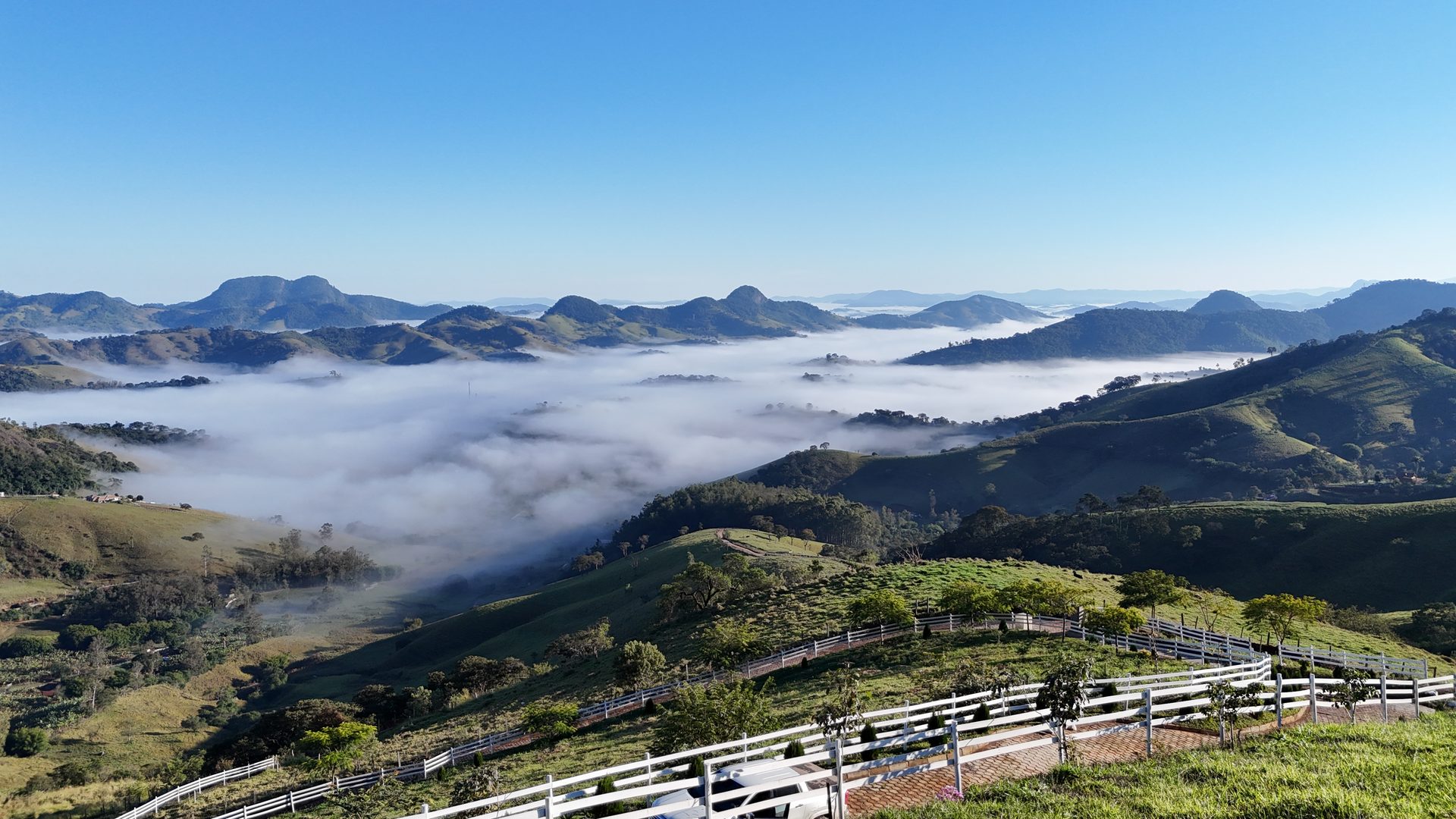 Vista aérea do mar de nuvens no vale com cerca branca em primeiro plano