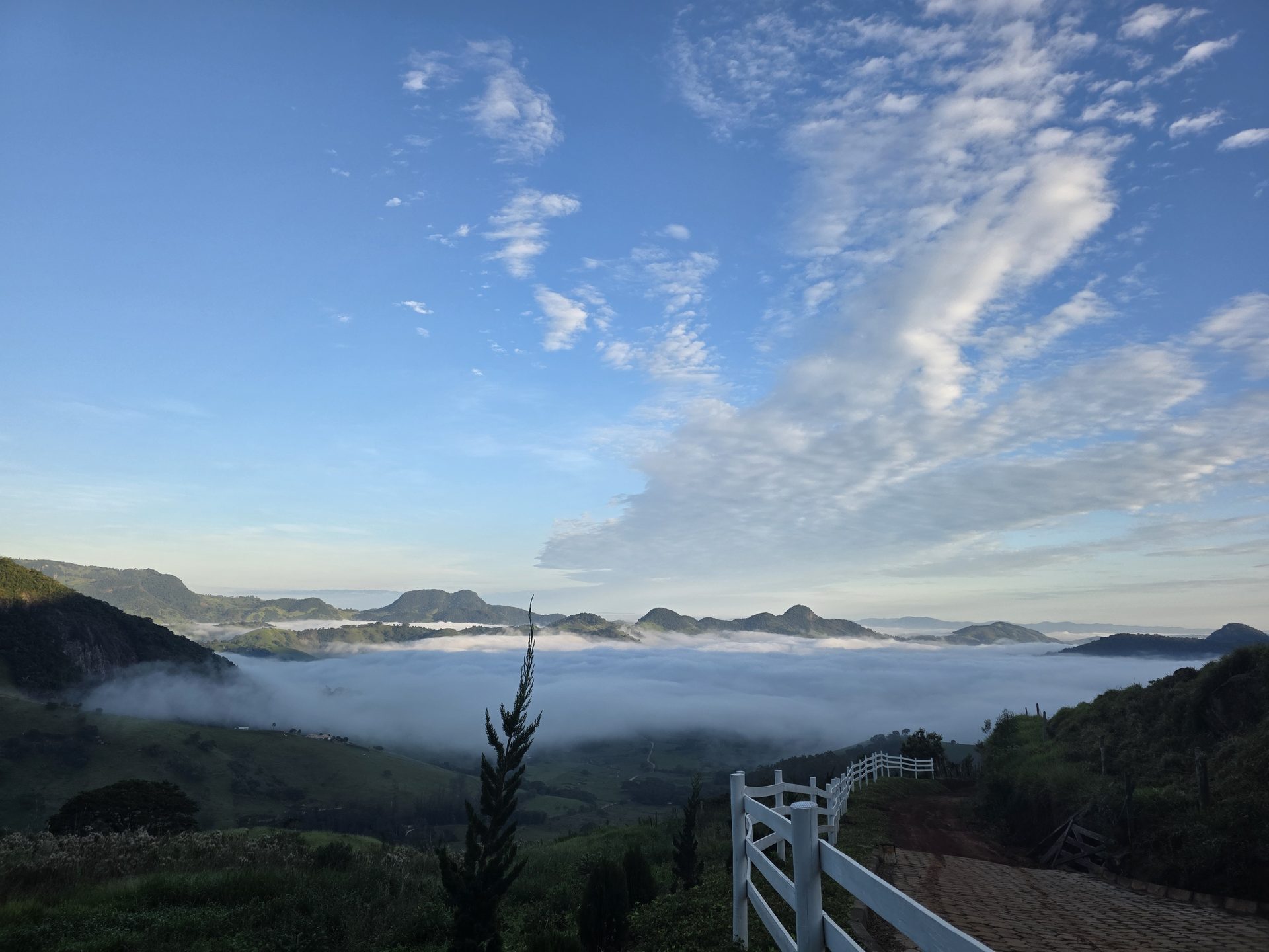 Mar de nuvens ao amanhecer com cerca branca