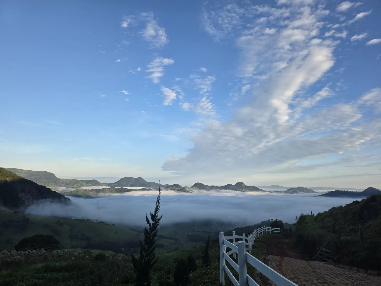 Mar de nuvens ao amanhecer com cerca branca